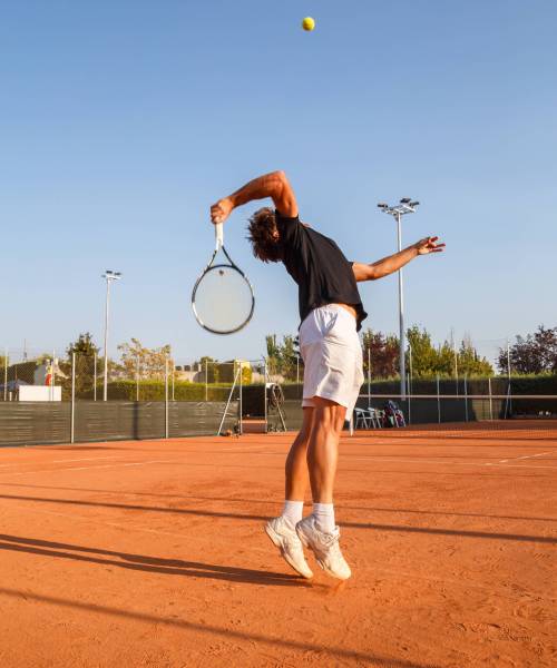 man-playing-tennis-court-against-clear-blue-sky
